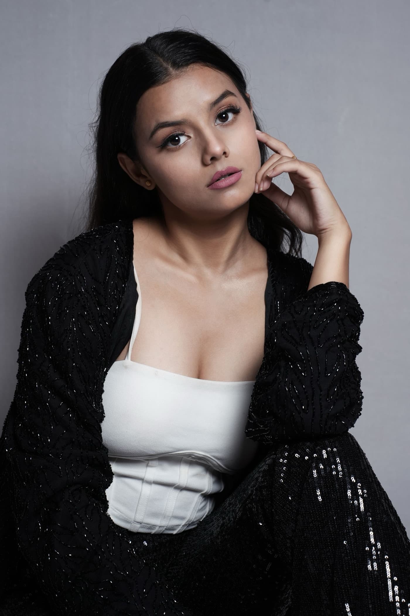 Ishani Rao in a black jacket and white corset top, looking at the camera