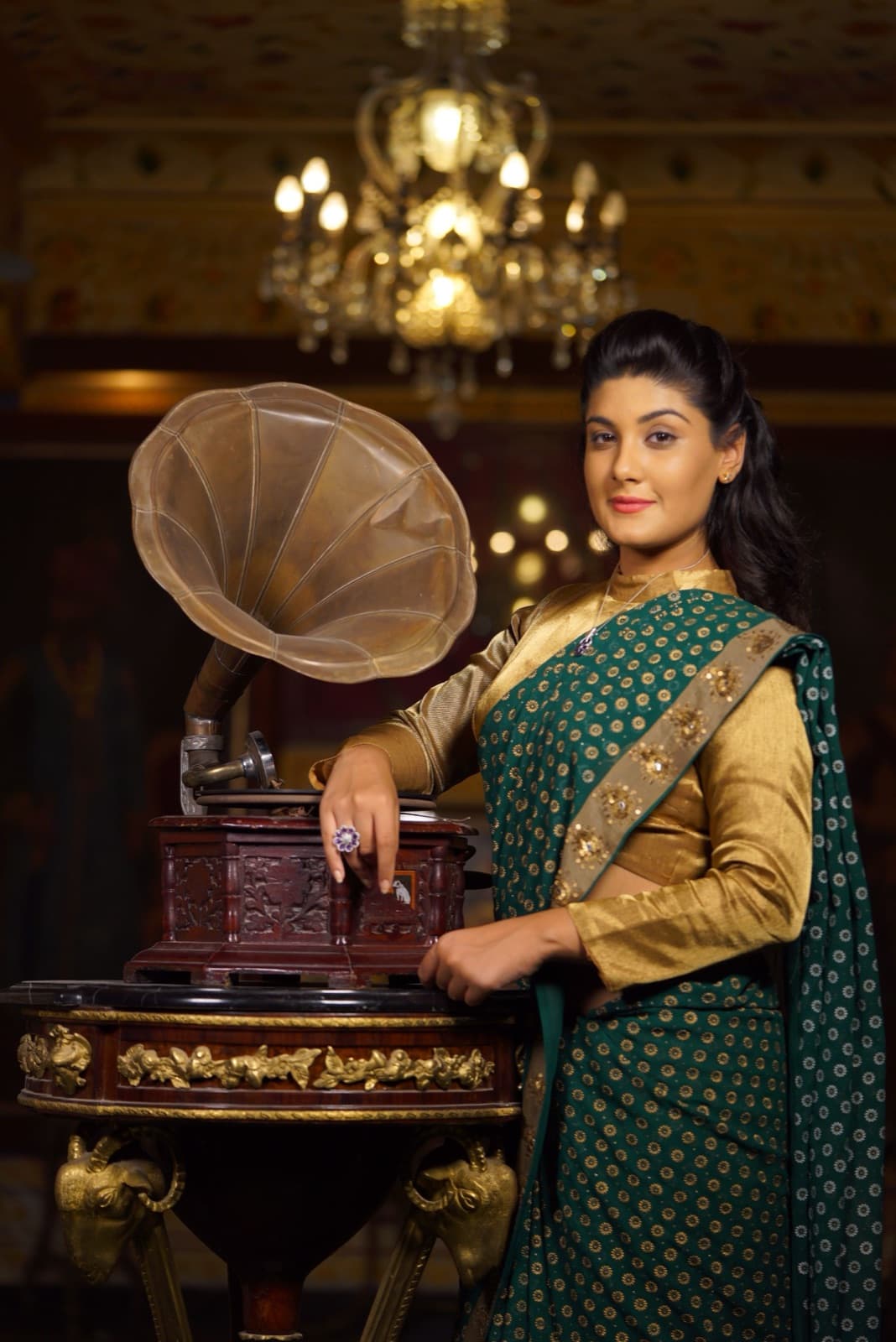 Noor Haider beside a gramophone under a chandelier